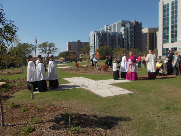 Bishop Morlino blesses the 14th Station, today, September 14th. The large stone blocks you can see scattered here and there among the landscaping are, poignantly, burnt stones from the old Cathedral.